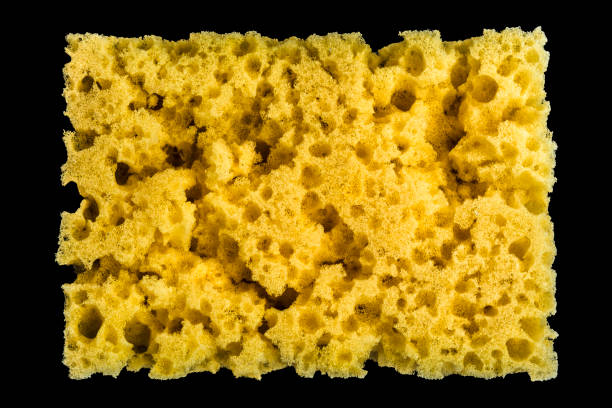 istock worn yellow sponge for washing dishes on black background, abstract background 994513700