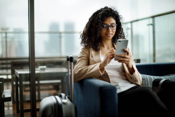 jeune femme d’affaires à l’aide de téléphone portable - arrival airport airport lounge flying photos et images de collection