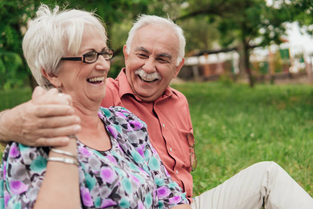 istock Smiling senior couple sitting on the grass and holding hands 994528420