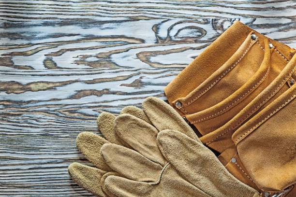 istock Leather protective gloves tool belt on wooden board 994538400