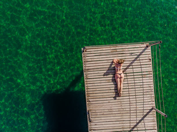 Young Woman Relaxing at The Sea Young Woman Relaxing at The Sea in Summertime jetty aerial stock pictures, royalty-free photos & images