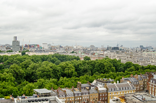View from a tall building of the trees of St James' Park in the middle of Westminster, London.  To the right are the Government ministries of Whitehall including the Treasury, Foreign Office and Ministry of Defence.  Beyond the park are the tall buildings of New Zealand House, University College Hospital and the Royal Opera House.  Cloudy summer afternoon.