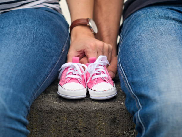 istock Couple holding hands tiny baby shoes 994596486