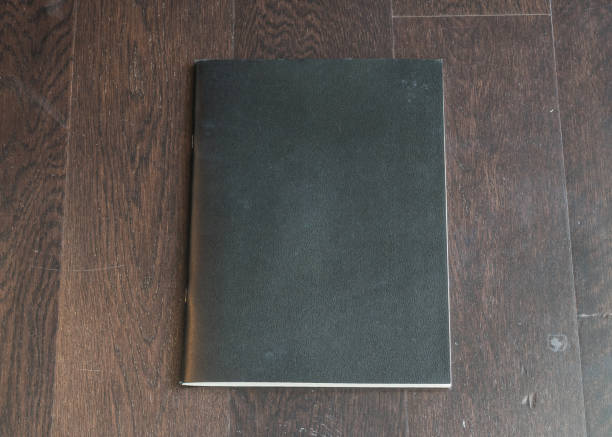 istock Book mockup blank black A4 leather cover for magazine, booklet, brochure, menu, diary mock-up design template on wooden table background 994621910