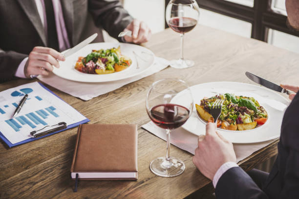 Close up. Two Businessmen Have Lunch with Wine. Discussion of Financial Successes at Meeting in Modern Cafe. Successful Partnership Concept. Discussion of Financial Successes at Meeting in Modern Cafe. Successful Partnership Concept. business lunch stock pictures, royalty-free photos & images