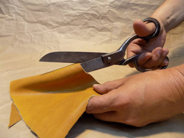 istock Tailor cut piece of yellow leather with old, but very sharp scissors 994645224