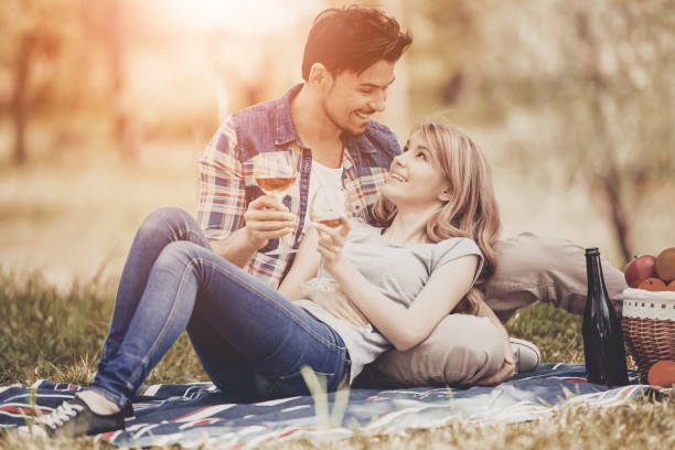 istock Couple Lying on Grass and Drink Wine in Park. 994645410
