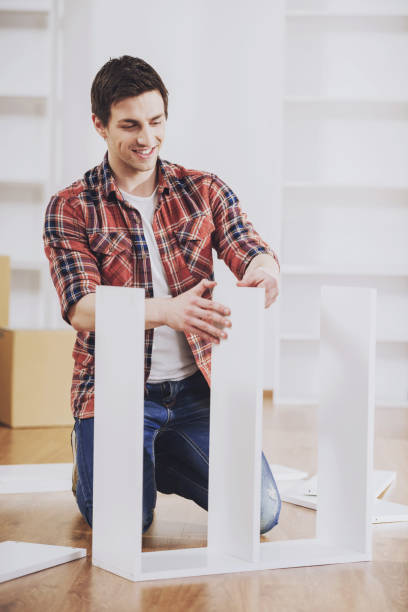 istock Smiling Man Installing Furniture in New Home. 994645996