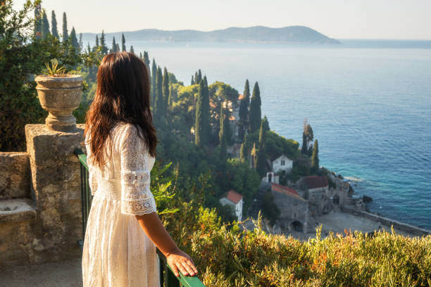 Traveller enjoys scenic view of Trsteno, Croatia. Woman traveller enjoys scenic view of Adriatic coast in Trsteno, Dalmatia, Croatia. Tourist attraction near Dubrovnik old town. arboretum stock pictures, royalty-free photos & images
