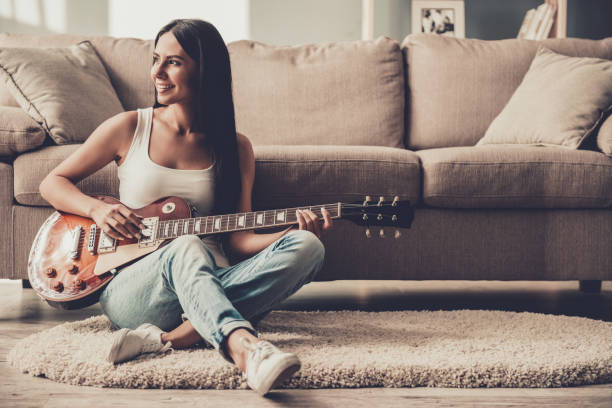 Young Smiling Woman Sitting and Playing Guitar.