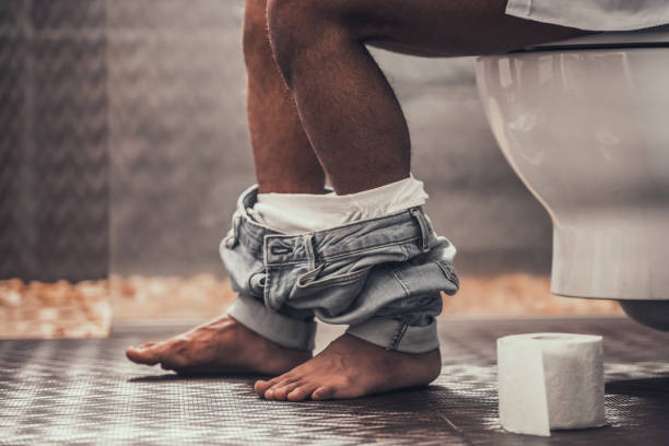 Close up Young Afro-American Man Sitting on Toilet stock photo