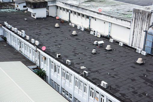 Many air condition compressor and air vent with some television satellite on roof deck of old building background
