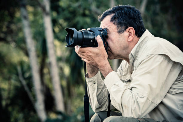 istock Hispanic mature man looking through binoculars on the forest 994664970