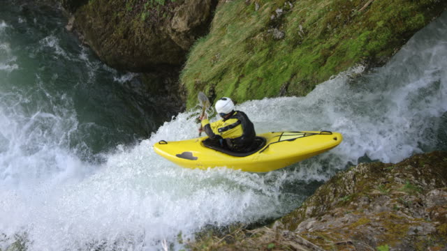 SLO MO Kayaker in a yellow kayak running a waterfall and diving into the plunge pool