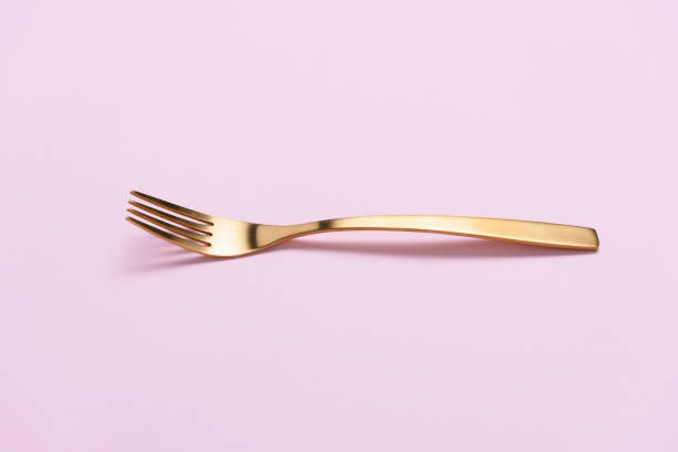 A gloden folk isolated on pink background with negative space.
