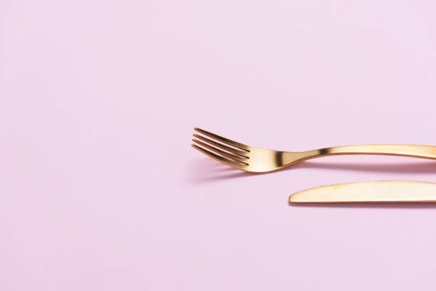 istock Golden fork and knife on light pink background with negative space. 994710222