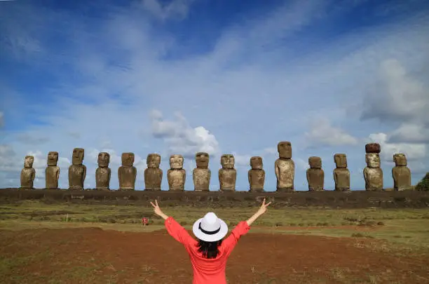 Photo of One female raising her arms happily in front of Moai statues of Ahu Tongariki on Easter Island, Chile, South America
