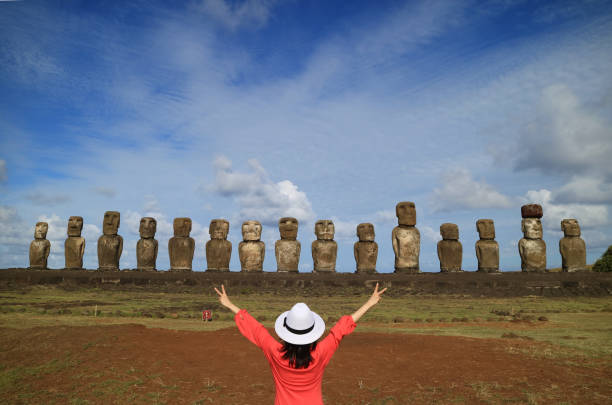uma fêmea levantar seus braços alegremente na frente estátuas moai do ahu tongariki na ilha de páscoa, chile, américa do sul - polynesia moai statue island chile - fotografias e filmes do acervo