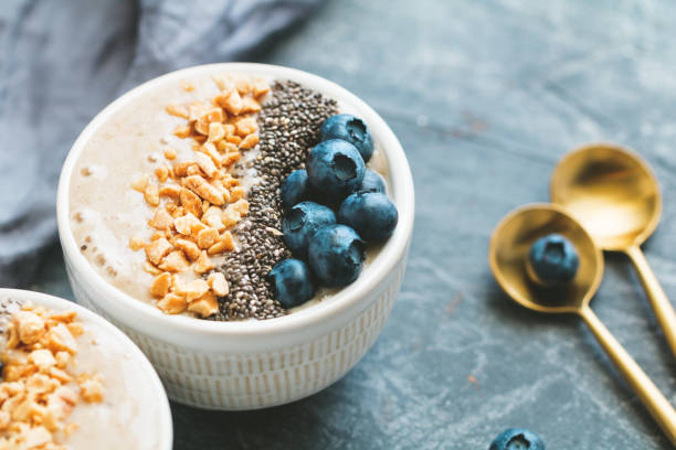 istock Smoothie bowl with banana, chia seeds, fresh blueberry and nuts over grey table. 994735838