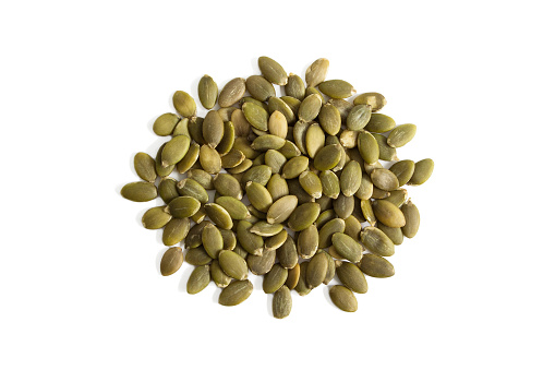 Isolated uncooked green pumpkin seeds on a white background from above.