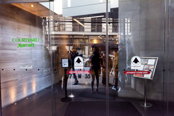 Manhattan NYC buildings of midtown Herald Square, avenue road, signs for Courtyard Marriott, Monarch bar, people walking on 35th street sidewalk reflection New York City, USA - April 6, 2018: Manhattan NYC buildings of midtown Herald Square, avenue road, signs for Courtyard Marriott, Monarch bar, people walking on 35th street sidewalk reflection walking into glass door stock pictures, royalty-free photos & images