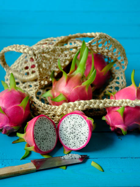 istock Market fresh Thai white Dragon Fruit on an old worn wood turquoise colored table background, some in a reusable string bag and one cut by a kitchen knife in a cross section to show the inside. 994753480