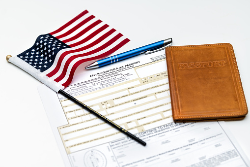 Fairfax, USA - April 11, 2018: U.S. Department of State application for US, American passport on table with pen, flag and passport case, cover