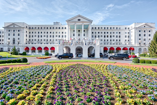 White Sulphur Springs, USA - October 20, 2017: Greenbrier Hotel resort exterior entrance with landscaped flowers, lawn, cars, in West Virginia
