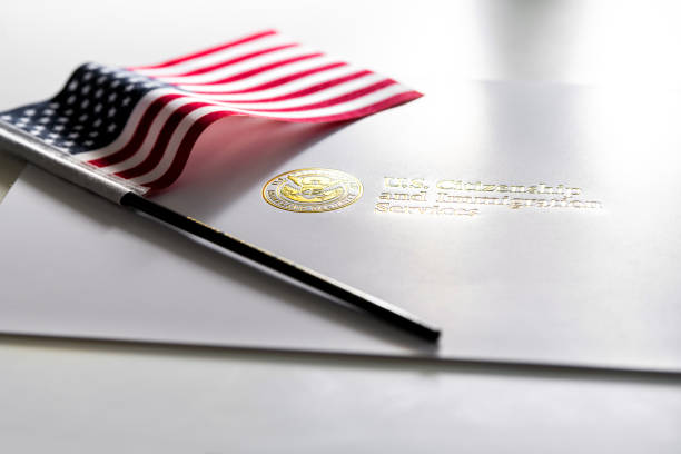 美國公民和移民服務信封, 白色資料夾為歸化證明在桌與美國旗子 - 公民 個照片及圖  片檔