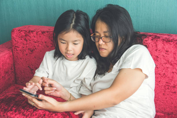 istock young mom and her little daughter are using a smartphone on sofa at home 994759274