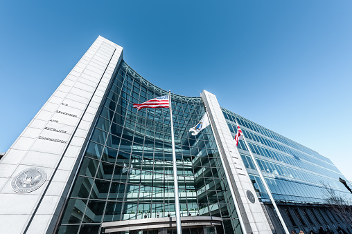 Washington DC, USA - January 13, 2018: US United States Securities and Exchange Commission SEC entrance architecture modern building sign, entrance, american flag, looking up sky, glass windows reflection