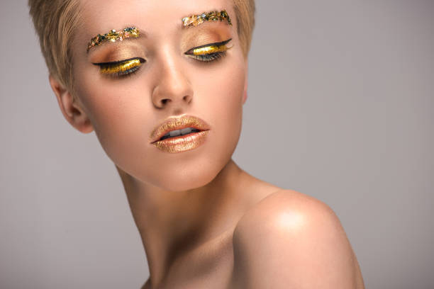 istock attractive woman with golden shiny makeup looking down isolated on grey 994761642