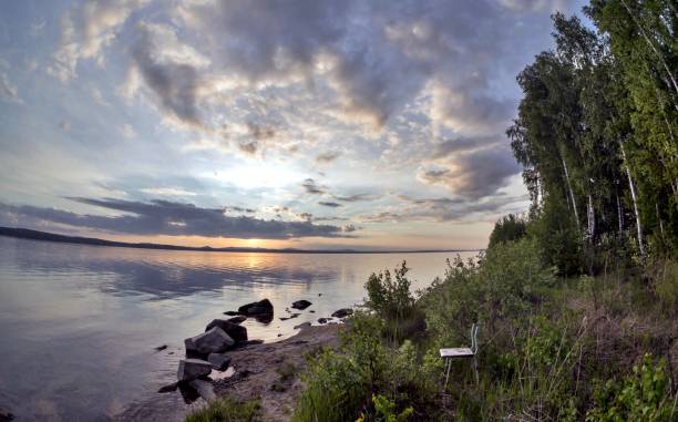 istock gray evening sky over the lake, orange sun, fish-eye 994778468