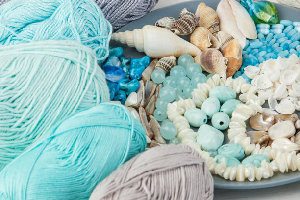 istock Knitting threads and gray plate with beads and seashells 994783726
