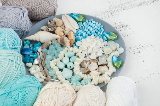 istock Knitting threads and gray plate with beads and seashells 994783852