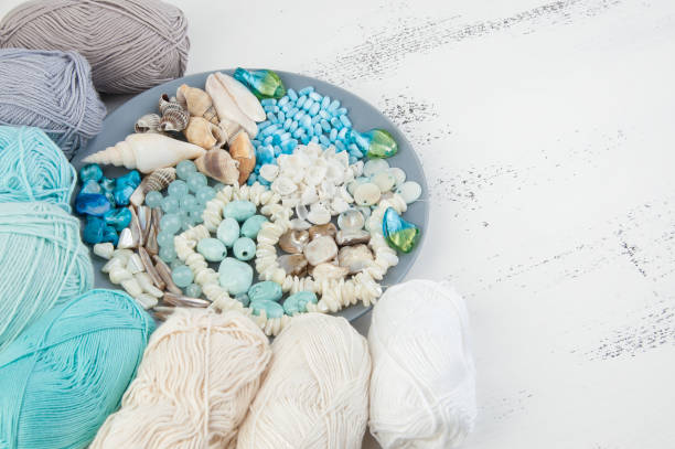 istock Knitting threads and gray plate with beads and seashells 994783910