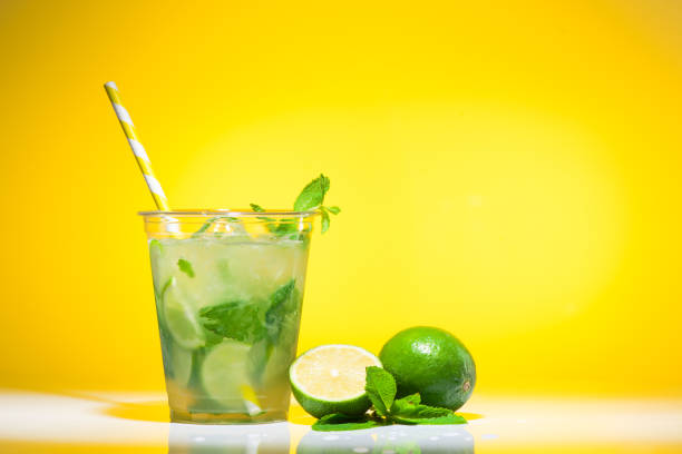Female hand holding decorated mojito cocktail at the beach