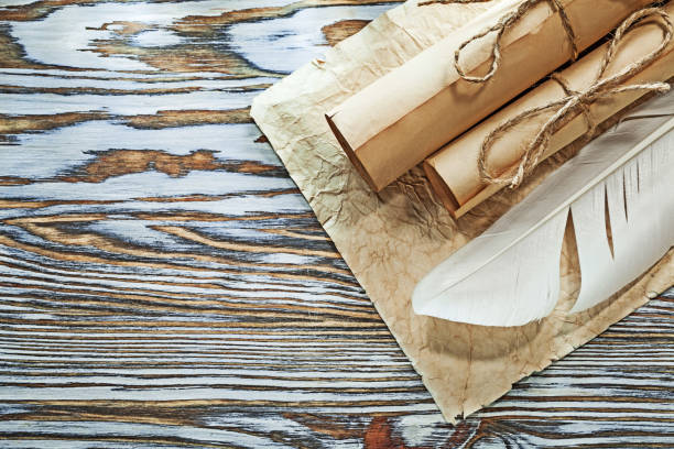 istock Medieval paper rolls crumpled document plume on wooden board 994796044