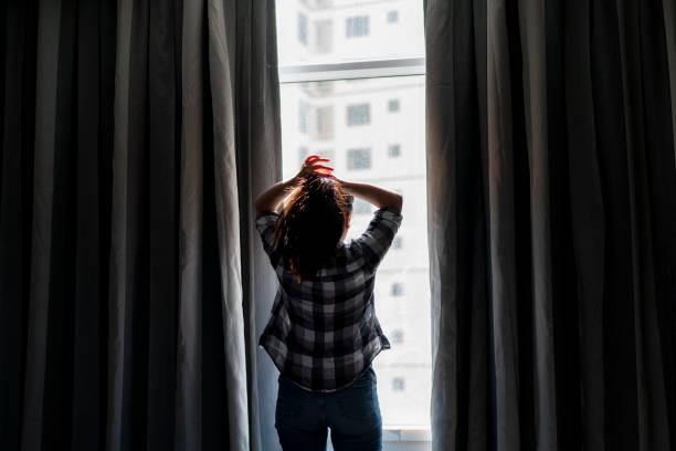 istock girl standing beside window, combing long hair 994801274