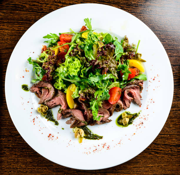 istock Appetizing meat dish served with tomatoes and lettuce in the whi 994804598