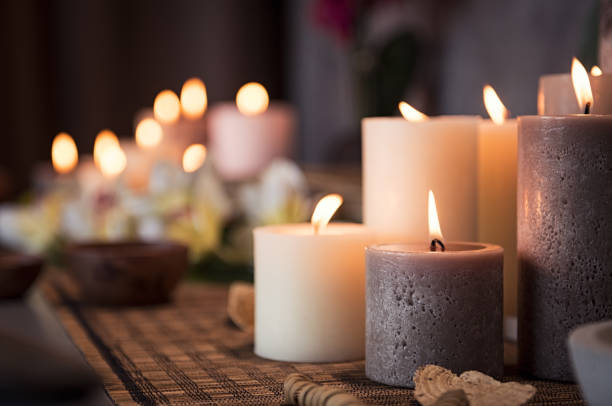 Spa setting with aromatic candles Closeup of burning candles spreading aroma on table in a spa room. Beautiful composition with grey and white candles for spa treatment. Zen and relax concept. candle stock pictures, royalty-free photos & images