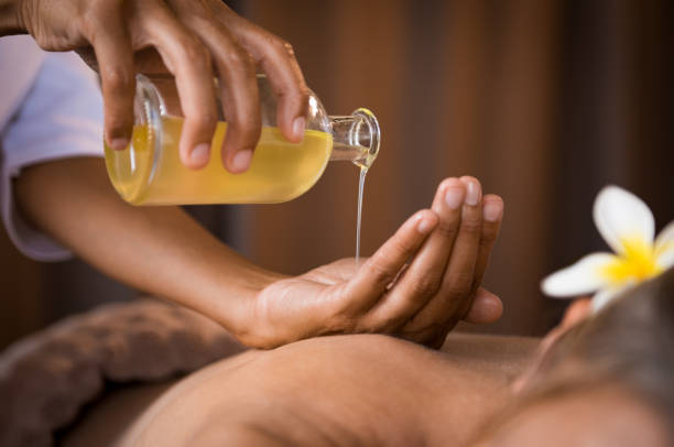 Therapist pouring massage oil at spa Closeup of masseur hands pouring aroma oil on woman back. Masseuse prepare to do oriental spa procedure for relaxing treatment. Therapist doing aromatherapy oil massage on woman body. health farm stock pictures, royalty-free photos & images