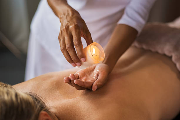 Candle massage at spa Closeup of masseuse hands pouring wax from a candle on back of mature woman. Beautiful woman at salon spa getting a body oil treatment candle with hot wax. Beauty therapist doing candle massage. candle wax stock pictures, royalty-free photos & images