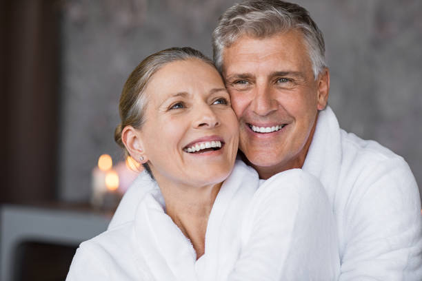 couple de personnes âgées embrassant à spa en riant - health spa couple spa treatment towel photos et images de collection