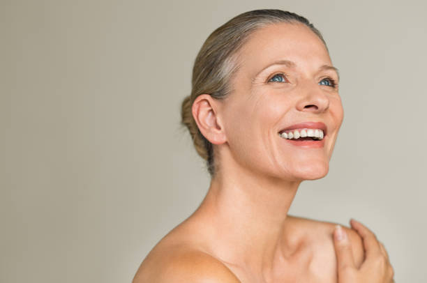 Beauty mature woman laughing Portrait of a cheerful senior woman smiling while looking away isolated on gray background. Happy mature woman after spa massage and anti-aging treatment on face. mature beautiful woman stock pictures, royalty-free photos & images