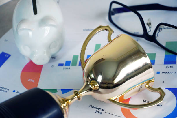 trophy and white piggy bank and glasses on paper analasis, win concept. - analasis imagens e fotografias de stock