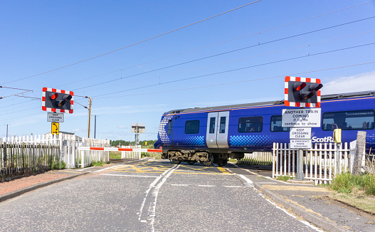 Gailes, Scotland, UK - July 06, 2018: A Train crossing the old Railway Crossing at Gailes in the west of Scotland.
