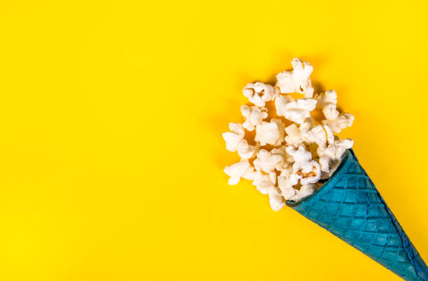 istock Spattered popcorn on a yellow background. Sweet popcorn in waffle cone. Copy space 994817710