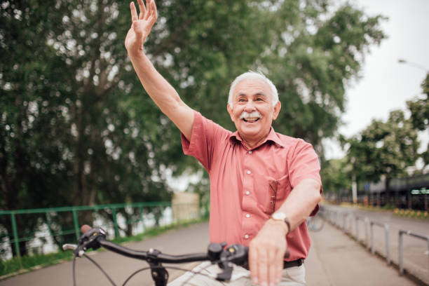 istock Old man riding a bike and waving his hand 994820042