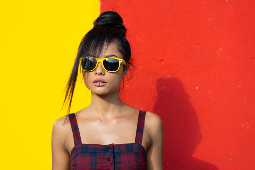 Beautiful young woman posing in front of colored wall.